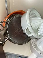 Photo of a white citrus juicer, metal mesh sieve, and handheld sifter or small sieve