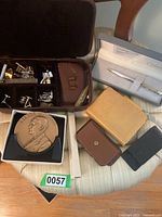 Full view of men's jewelry items including cufflinks, wallets, Colibri pen in case, and George Eastman plaque.