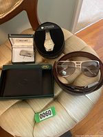 View of all items in the lot - Citizen watch in box, Colibri money clip in box, Seville wallet in box, retro sunglasses, and a brown leather belt.