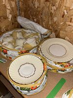 Photo showing stacked teacups upside down, saucers, and side plates with floral protective covers.