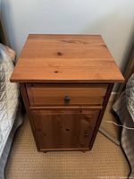 Front view of wooden night table showing drawer and cabinet door with knobs.