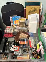 Image showing a variety of office supplies including tape rolls, folders, a calculator, and a perpetual calendar on a green surface.
