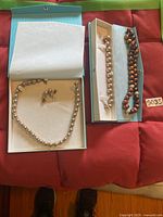 Full view of two pearl necklaces and one pearl bracelet with earrings in presentation cases.