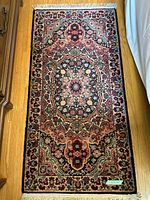 Single flat-laid Oriental style rug in red, navy, cream floral medallion pattern with fringe