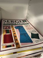 Sewing project book titled 'Serge: A Simple Project' on shelf.