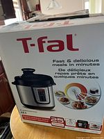 Box of T-fal 6 quart electric pressure cooker showcasing product image and highlights like 25+ built-in presets.