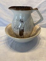 Ceramic pitcher with illustration of a person working with a barrel, brown glazed rim and handle