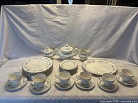Full set of J&G Meakin Burlington dinnerware laid out on white cloth including platters, plates, cups, saucers, teapot, creamer, and sugar bowl.