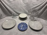 Overview of lot with all items: rooster figurine, blue Willow plate, two large Limoges handled plates, nine salad plates stacked, and Bubble & Star glass compote bowl.