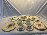Full view of all plates and teacup sets arranged together showing floral designs and condition.