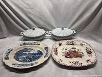 Four serving pieces including two white porcelain covered dishes, blue and white Mason's Ironstone China rectangular platter with fruit basket design, and Johnson Bros platter with English Gardens colorful fruit and floral design and browning.