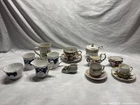Photo showing the entire collection of fine bone china and porcelain items including cups, saucers, creamers, sugar bowls, jam jar, and figurine.