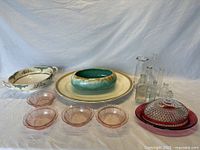 Overall group showing pottery items, pink Depression glass dishes, glass butter dish with lid, and vintage bottles.