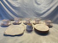 Full set of Tuscan china items including teacups, saucers, plates, and creamer on white cloth background.