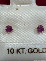 Pair of 10KT gold stud ruby earrings shown on display card reading '10 KT GOLD'