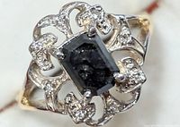 Top view showing emerald-cut black diamond center and white diamond scroll setting