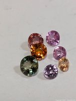 Six loose fancy color sapphire gemstones displayed on white background.