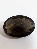 Oval faceted smokey quartz gemstone on a white background showing color and cut facets