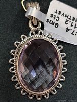 Close-up front view of silver amethyst pendant with faceted oval gemstone and decorative bezel.