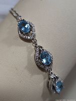 Close-up of the three oval blue topaz stones with clear stones surrounding each, showing the detailed silver setting