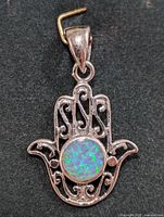 Front clear image of the silver Hamsa hand pendant with blue-green iridescent opalite stone in the center.