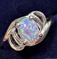 Close-up front view showing oval opalite stone set in polished sterling silver with decorative swirling on the band.