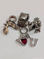 Four silver charm beads in Pandora style including flamingo, car, cupid, and I heart U design with stones