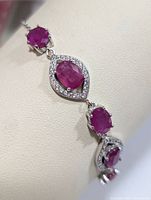 Close-up of the bracelet showing the oval and round ruby settings with silver and small clear stones around central rubies.