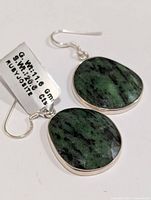 Close-up of oval faceted Ruby Zoisite earrings with tag showing weights and stone type