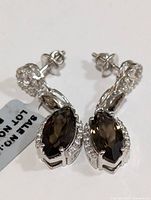 Pair of silver earrings featuring marquise-shaped smokey quartz stones with small clear stones surrounding them, shown from the front.