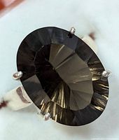 Close-up front view of silver ring with large oval faceted smokey quartz gemstone showing color and faceting detail