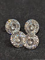 Close-up photo of four round Moissanite gemstones showing brilliance and cut.