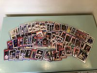 Large spread of assorted baseball, basketball, and football trading cards arranged on a surface showing front images of multiple players in action and posed shots.
