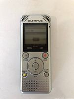 Front view of Olympus WS-801 digital voice recorder showing LCD screen with menu, control buttons including STOP, REC, ERASE, and SCENE INDEX, speaker at the bottom, and brand logo.