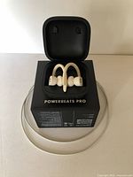 Beats Powerbeats Pro earphones in charging case, resting on product box, with charging cable around