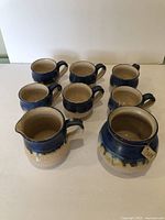 Photo showing 6 blue-glazed coffee cups and 1 coffee holder in front of them on a white background