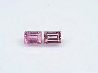 Two rectangular baguette-cut purplish pink sapphires placed side by side on a white background showing their color and facet details.