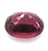 Close-up view of the faceted oval purplish pink Rhodolite garnet gemstone showing depth and brilliance from side angle.