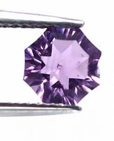 Close-up of the fancy cut amethyst held in tweezers showing the star-shaped facet pattern and visible internal inclusions.