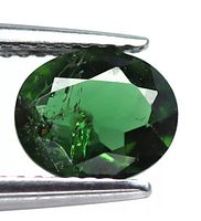 Close-up photo of a 1.22 Ct. oval cut chrome diopside gemstone held by tweezers showing color and internal inclusions.