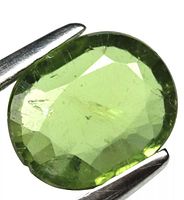 Close-up photo of an oval cut green apatite gemstone showing natural inclusions and facets.