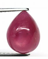 Front view of pear-shaped ruby cabochon gemstone held by tweezers, showing smooth polished surface and reddish color.