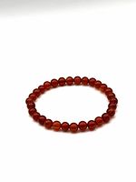 Photo of Carnelian 6mm bead bracelet laid flat showing the full circle of beads with uniform size and color.