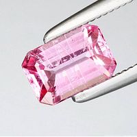 Close-up of octagon cut natural pink sapphire held by tweezers showing the facets and inclusions