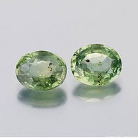 Pair of oval natural green sapphires from Australia, showing front view and surface inclusions