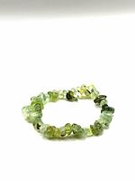 Prehnite tumbled stone chip bracelet with chips of varying green tones and translucent quality, arranged in a circle.
