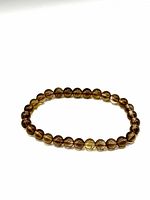 Full view of smoky quartz bead bracelet laid flat showing round beads with a translucent brownish-gray color and glossy finish.