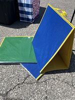 Two blue felt boards and one green felt board with yellow edging. Boards are square and freestanding with handles.