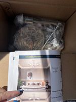 Chandelier parts and installation instructions inside box showing design and assembly visuals.