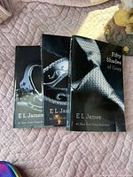 Three paperback books from the Fifty Shades of Grey series showing front covers on a quilted fabric surface.